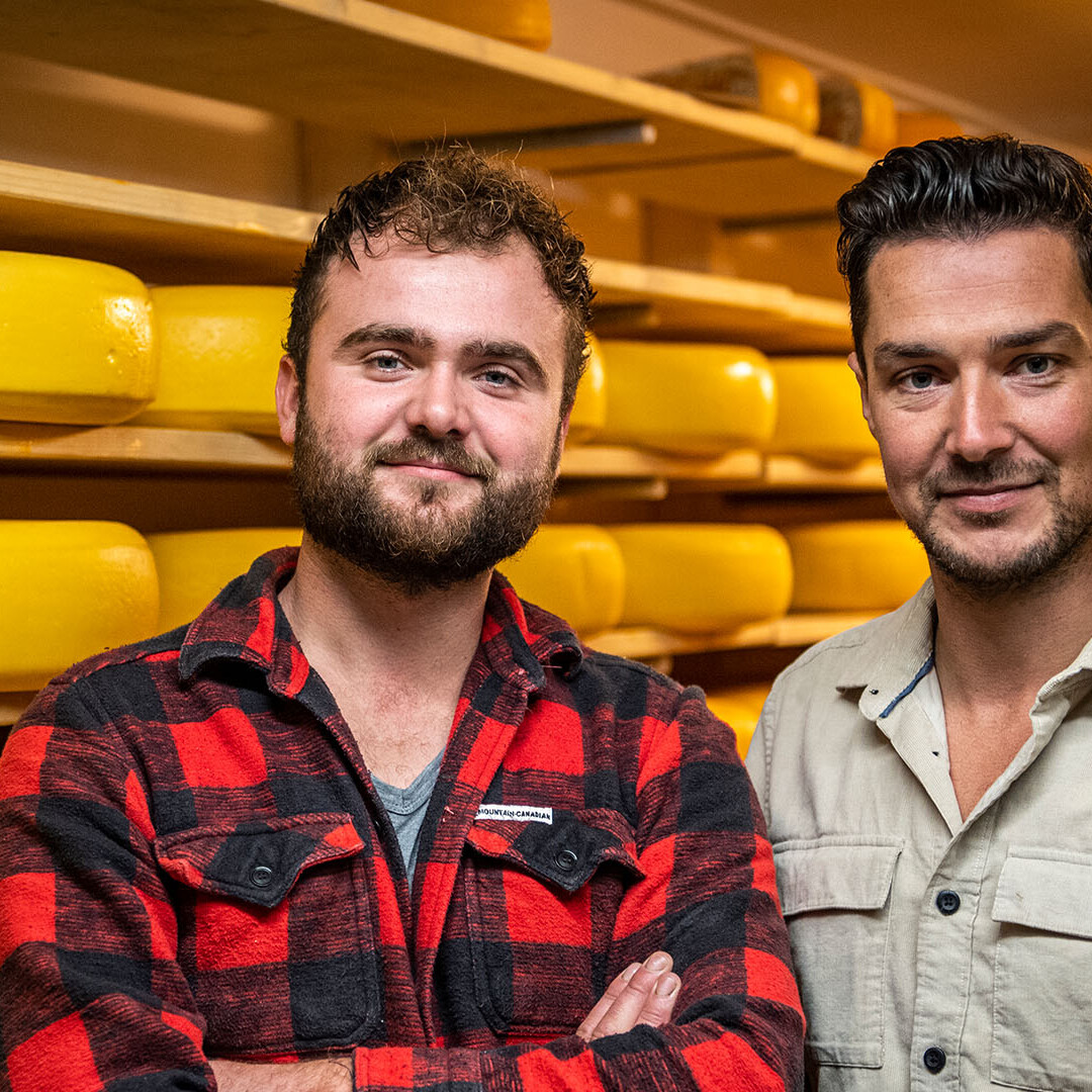 foto met Kaasmeesters Corné en Paul in de kaaskelder met hun goudse kazen op houten planken