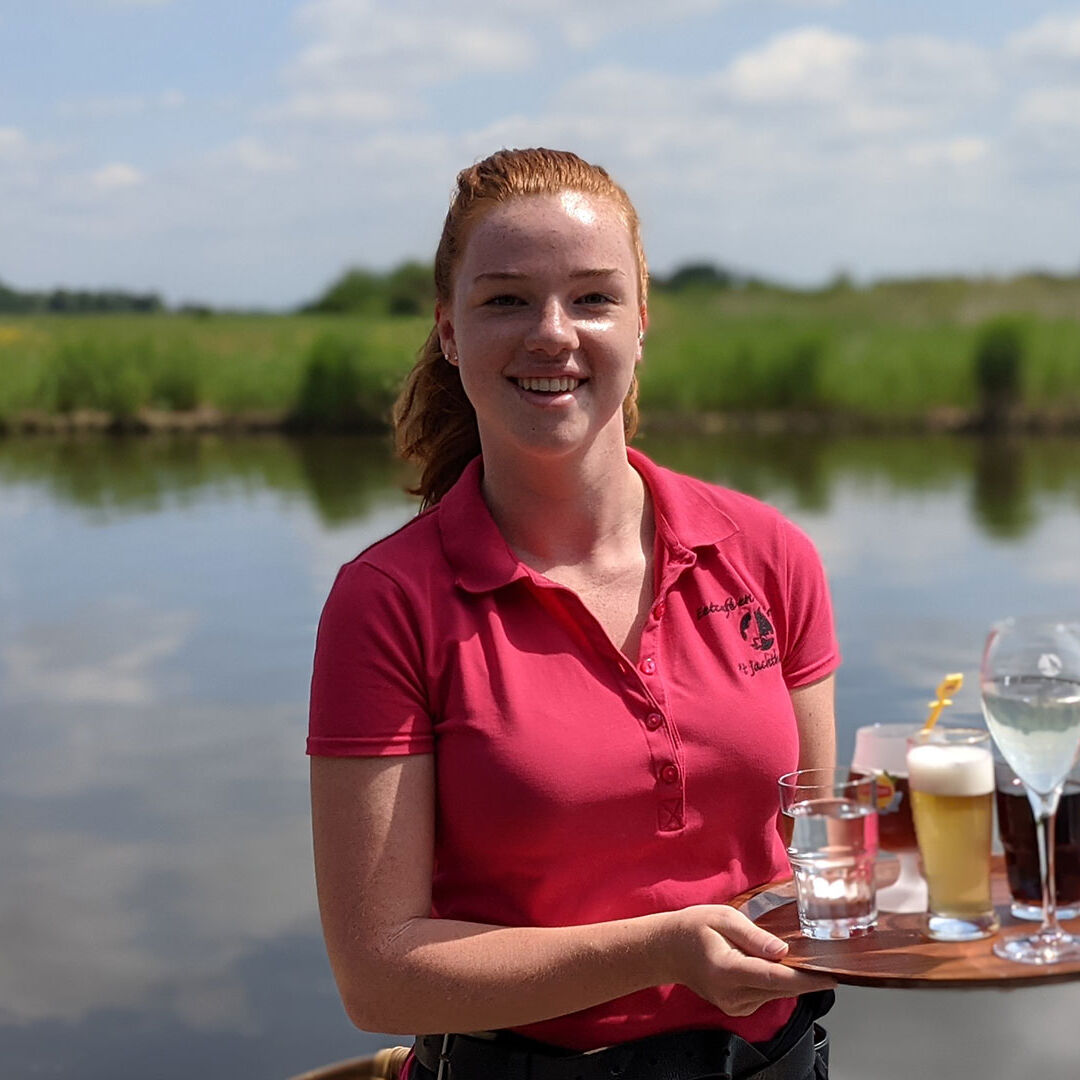 jongedame bedient op het terras van 't Jachthuis in de Foppenplas in Midden-Delfland met water en polderlandschap in de achtergrond