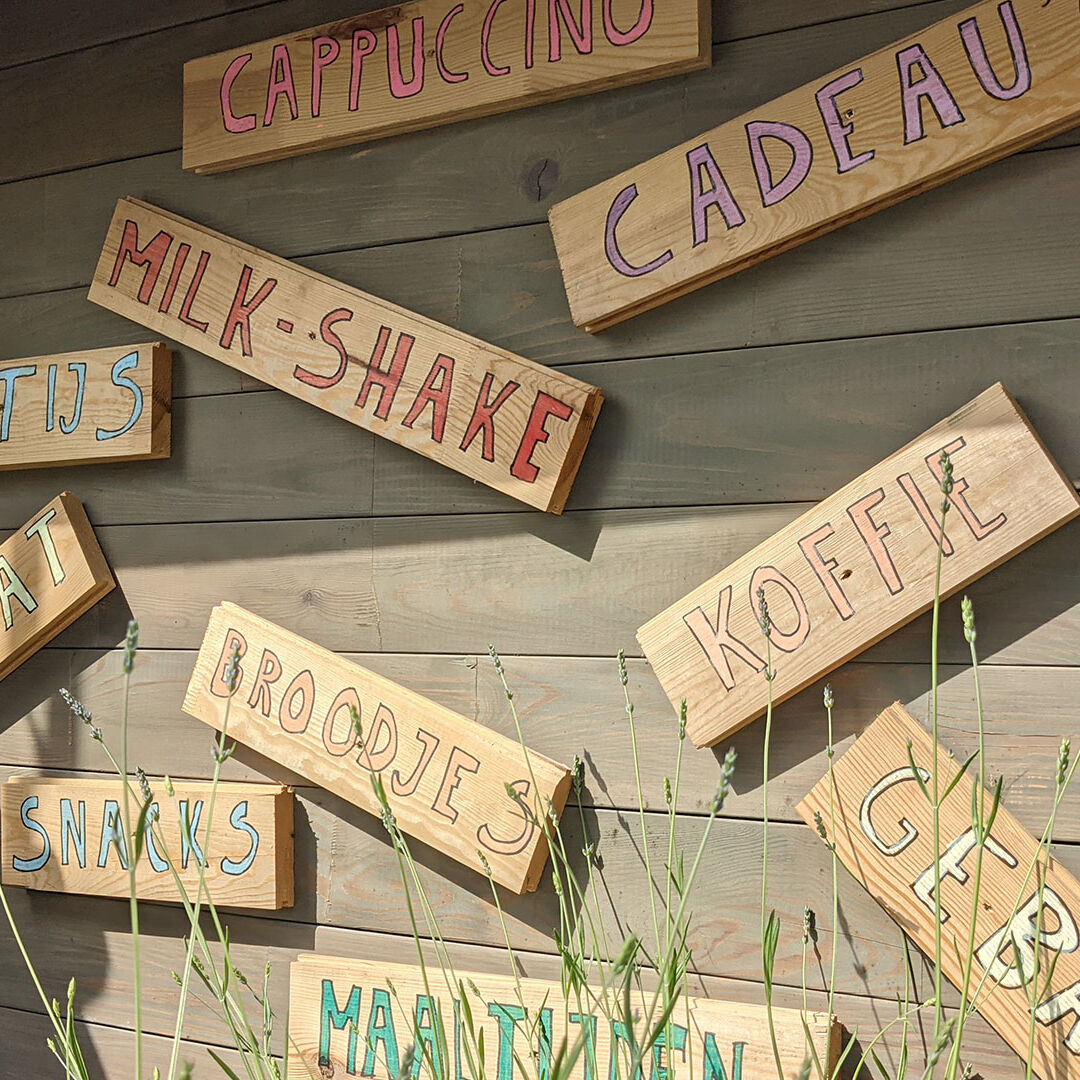 wand met houten bordjes waarop losse woorden staan van gerechten die te bestellen zijn zoals gebak, koffie, broodjes bij Paviljoen 't Middelpunt in Schipluiden in Midden-Delfland
