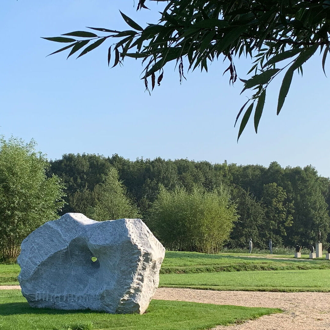rotsblok van ligt steen met een gat erin in het open polderlandschap van Midden-Delfland bij kunst landschapspark Land Art Delft