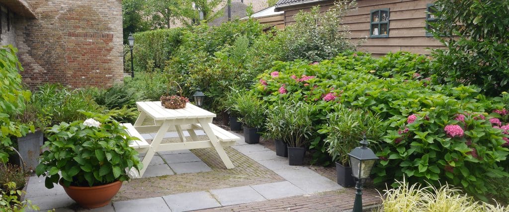 tuin bij B&B De Hooiberg in 'tWoudt in Midden-Delfland met groene achtertuin en witte picknicktafel