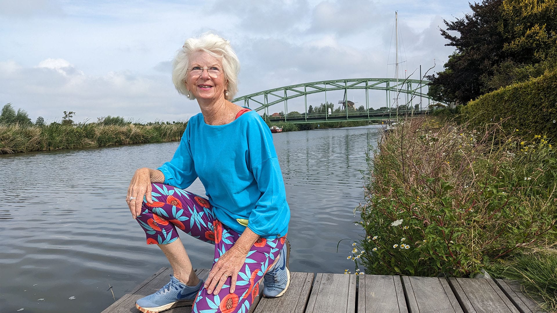 Annet Zwinkels uit Schipluiden knielend op een vlonder in de Vlaardingervaart met op de achtergrond de Trambrug op een zonnige dag in 2023 in Midden-Delfland