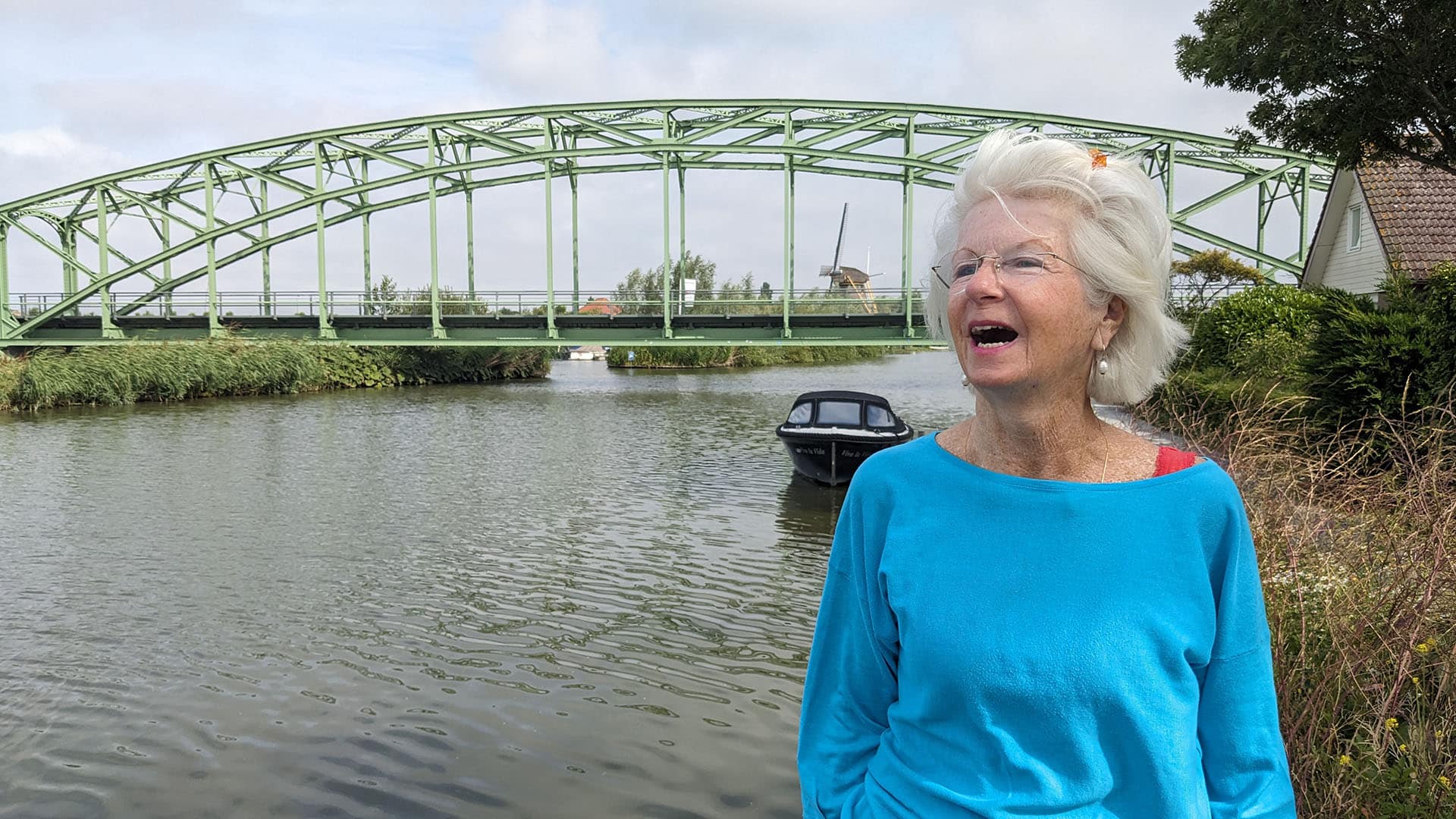 Annet Zwinkels lachend op de foto met in de achtergrond de Tramsbrug in Schipluiden in Midden-Delfland