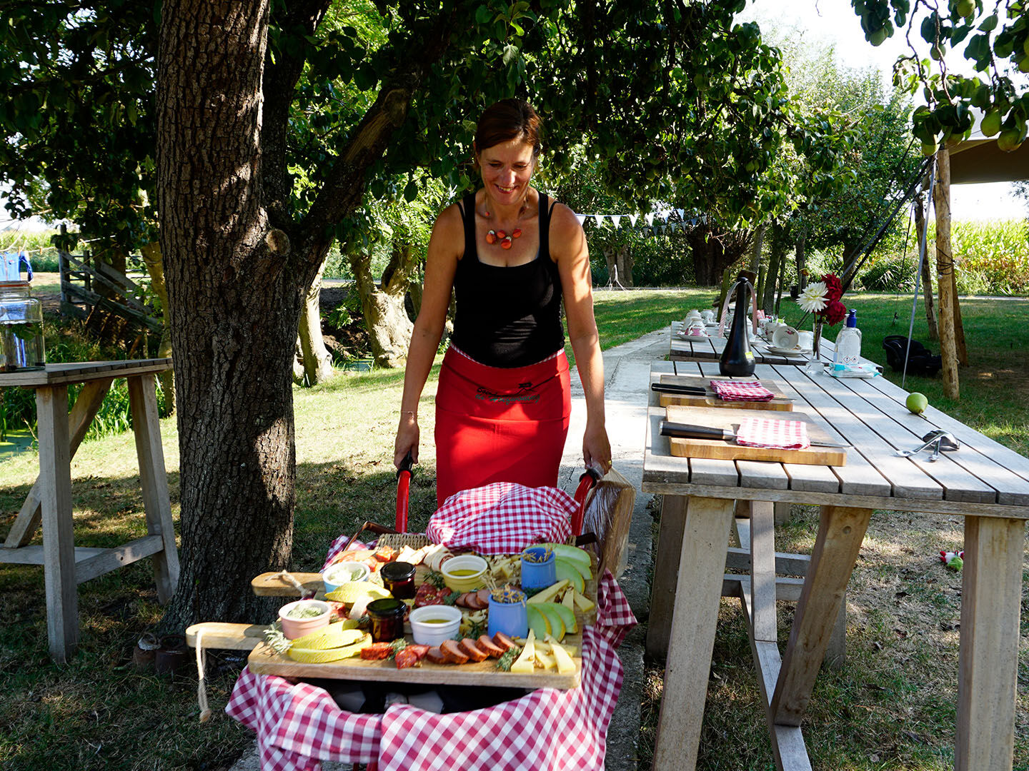 eigenaresse Jacqueline Nell met een rode kruiwagen met daarop een plank met de lunch bij Boerderij De Hoefwoning boerenpicknick