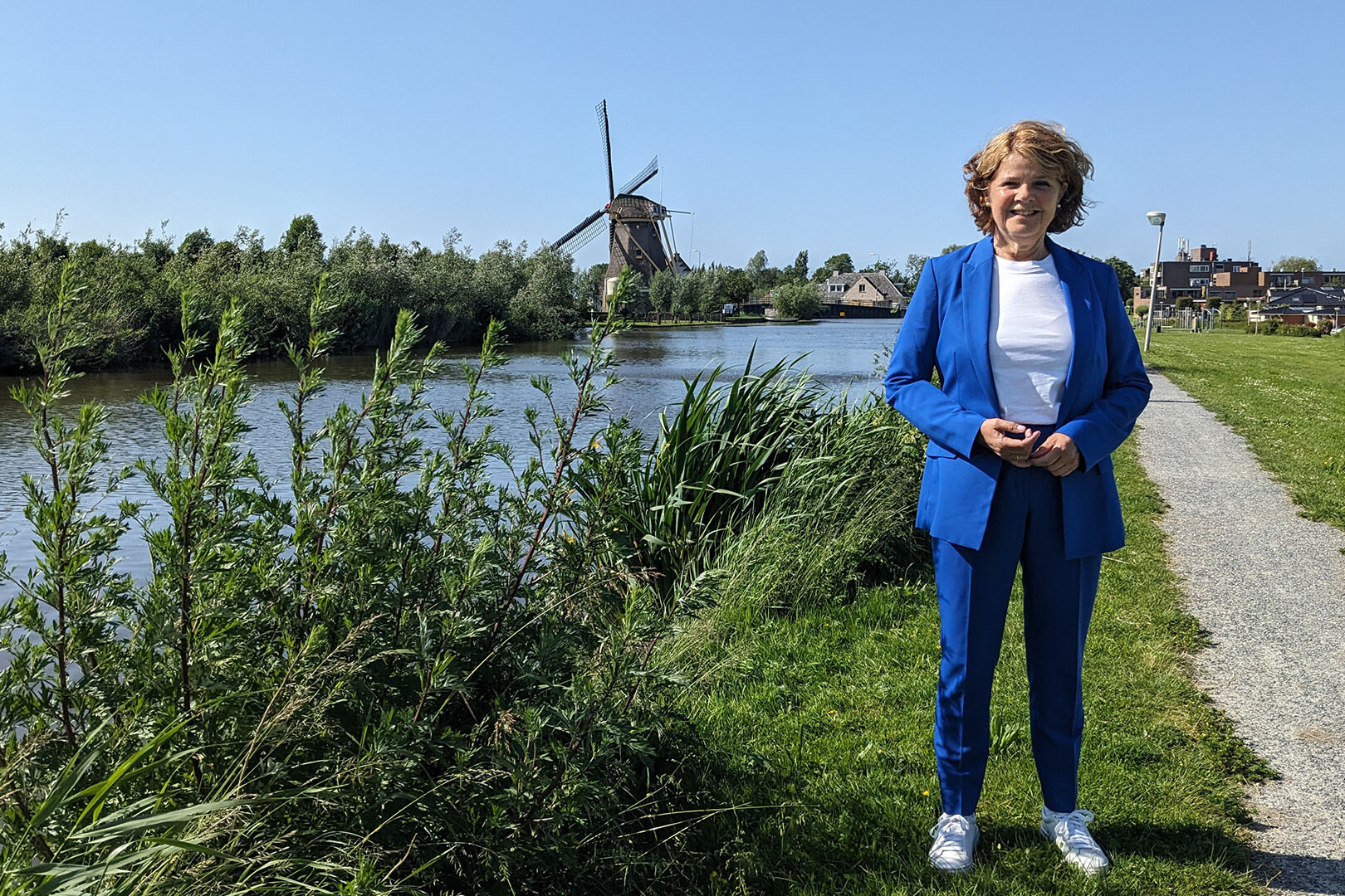 Marja van Bijsterveld op de dijk in Schipluiden naast de Vlaardingsevaart en in de achtergrond de molen op een zonnige dag voor de column MD door de ogen van