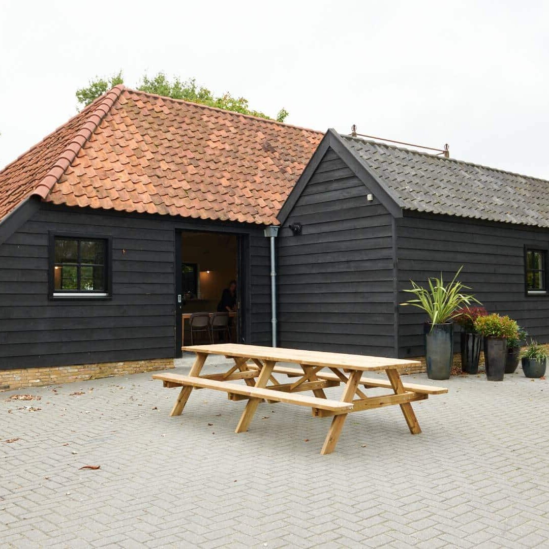 buitenaanzicht van een donker geverfde schuur waarin de vergaderlocatie is van Huize 't Woud in Schipluiden Midden-Delfland